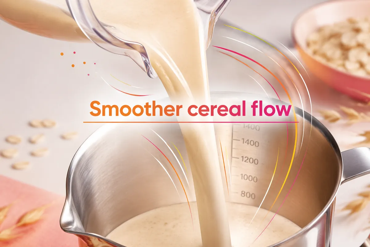 Smooth oat base pouring from a jug into a stainless measuring jug, labelled Smoother cereal flow